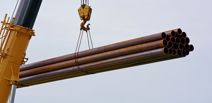 Industrial crane lifting metal pipes