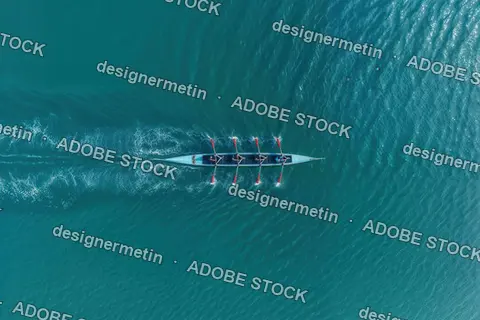 Aerial View Of A Rowing Team In Synchronization Moving Across Turquoise Water Creating Ripples And Reflections