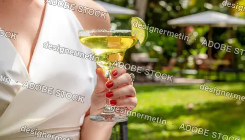 Woman Holding Margarita Cocktail In Summer Garden Party Setting With Lime Garnish And Red Painted Nails