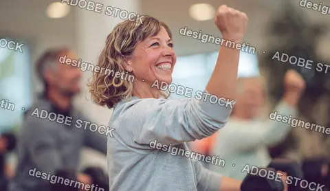 Smiling Mature Woman Raising Arm During Group Strength Workout In Modern Gym