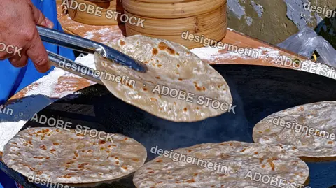 Hand Holding Flatbread With Tongs, Flatbreads Cooking On Hot Stove In Street Food