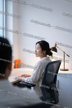 Thoughtful Asian Businesswoman Sitting At Modern Office Desk Talking With Colleague During A Meeting